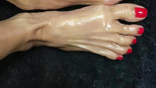Oiled sexy tiny feet with red toenail polish