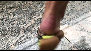 Wifes feet with red toenails crushing a kiwi fruit