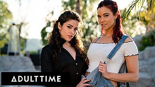 Jayden Cole and Victoria Voxxx pose outdoors in black shirt and denim overalls before lesbian bedroom play